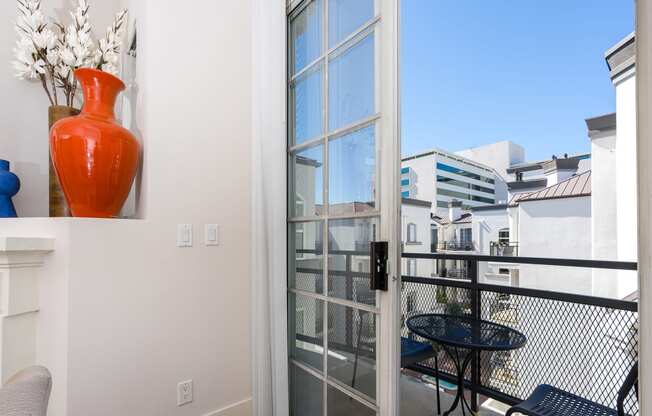 a balcony with a red vase on the wall and a glass door