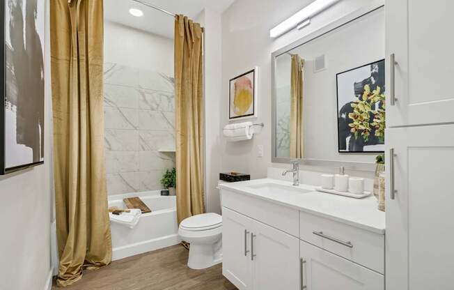 A bathroom with a white toilet, sink, and a marble wall.