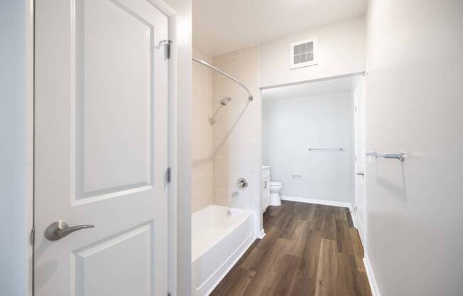 A white bathroom with a wooden floor and white walls.