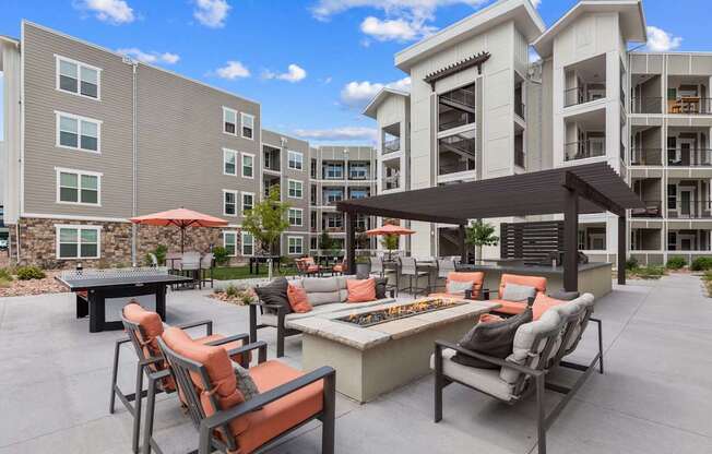 A patio with chairs and a table is surrounded by apartment buildings.