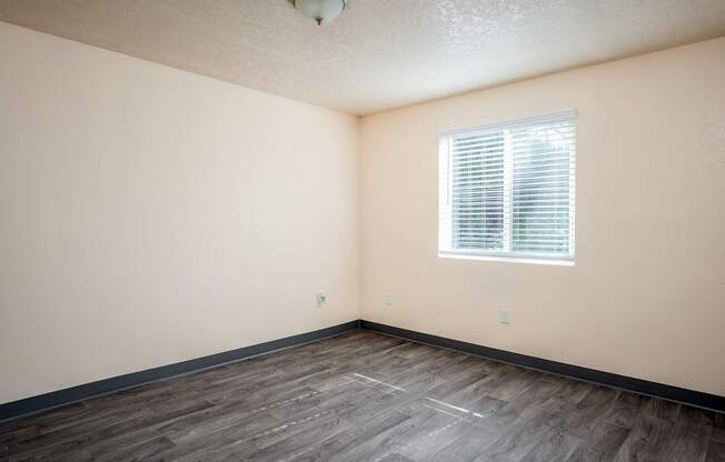 A room with a window and wooden flooring.