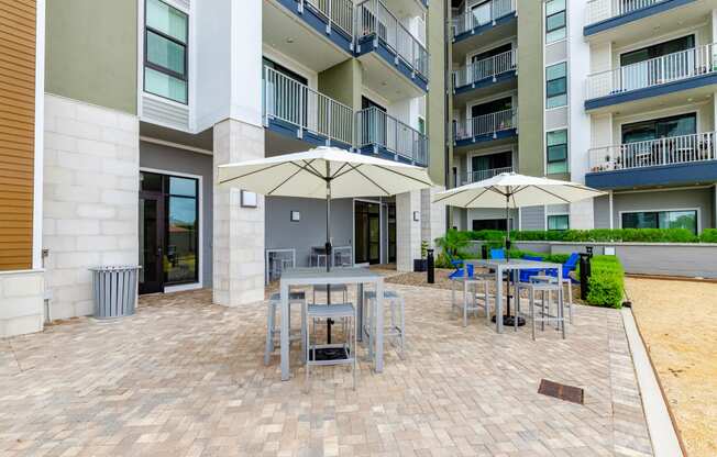 an outdoor patio with tables and umbrellas in an apartment building