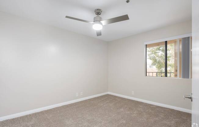 an empty room with a ceiling fan and a window at Huntington Terrace North Senior, Huntington Beach, CA 92648
