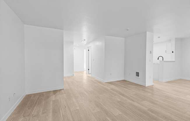 the living room and dining room of a new home with white walls and wood floors