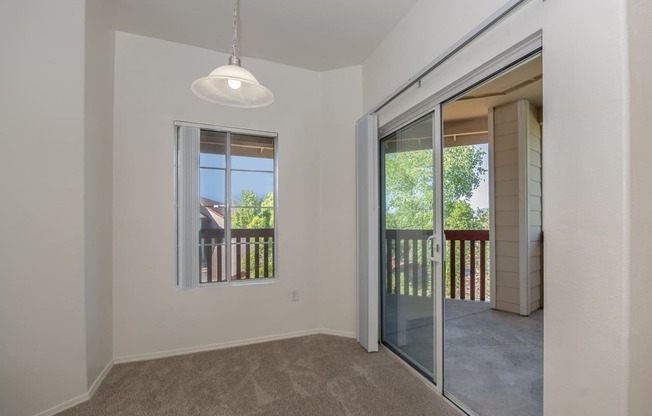 an empty living room with a sliding glass door to a balcony