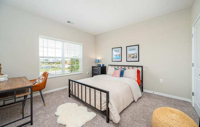 a bedroom with a bed and a desk and a window