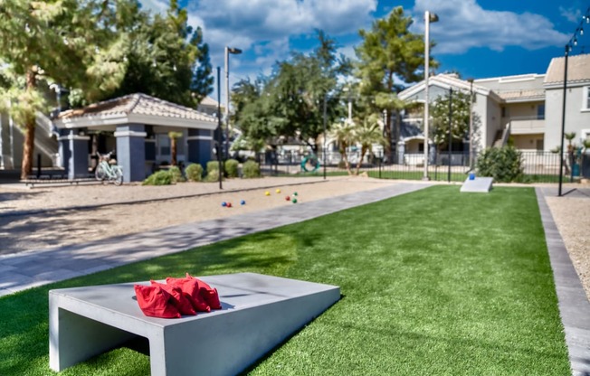 a red bouquet sits on a bench on the grass in front of a park