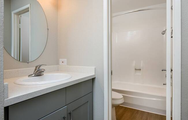 A bathroom with a sink, mirror, and bathtub.