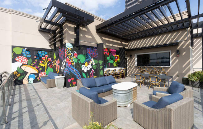 a patio with couches and tables and a mural on the wall