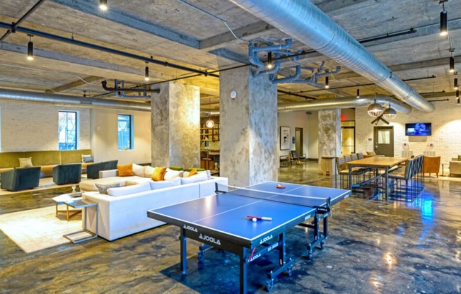a common room with a ping pong table and couches