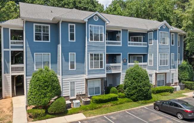 a blue apartment building with cars parked in front of it