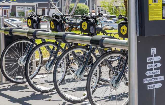 A row of bicycles are parked at a bike rack.