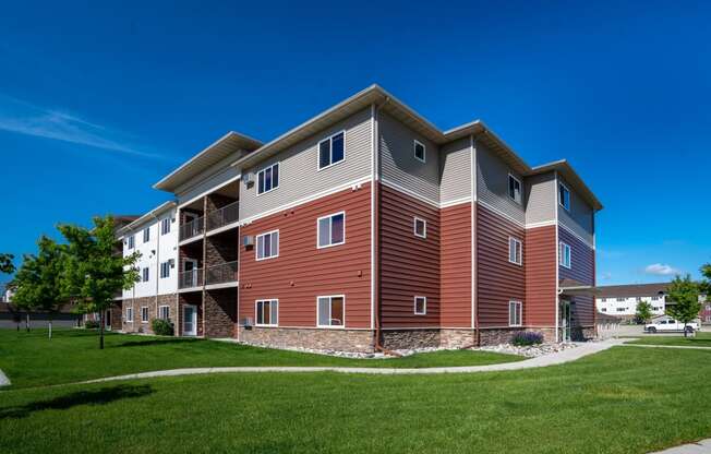 a modern apartment building with a green lawn and a blue sky