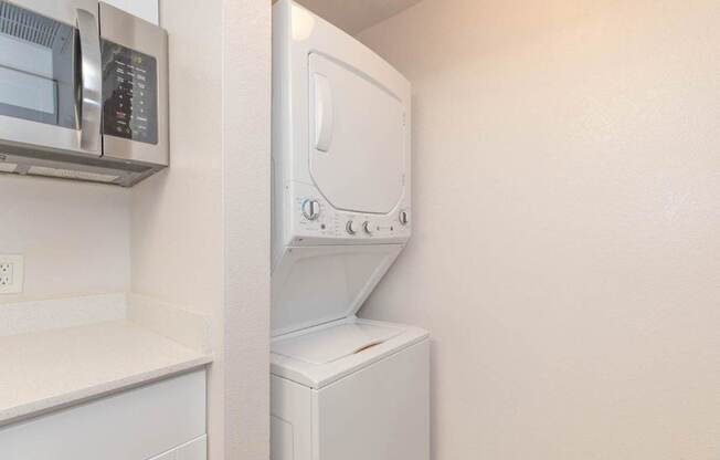 A white dryer is mounted on a wall next to a microwave.