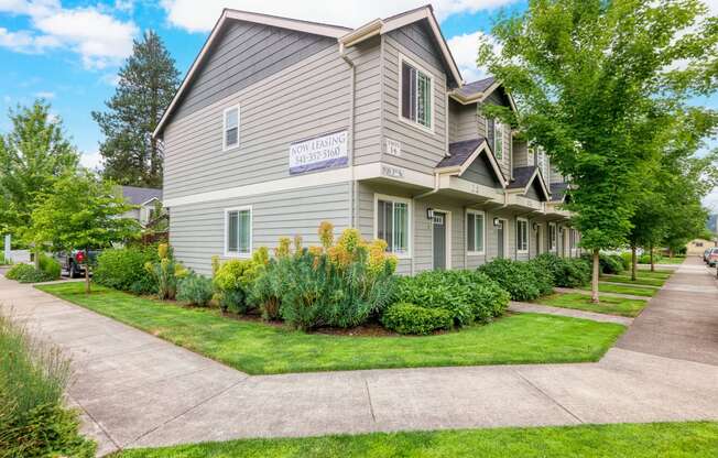 a house with a sidewalk in front of it and some trees