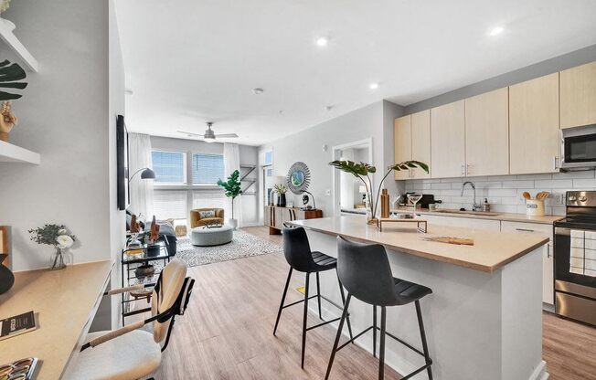 an open kitchen and living room with a bar and stools