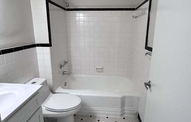 A white toilet sits in a bathroom with a black and white tile floor.