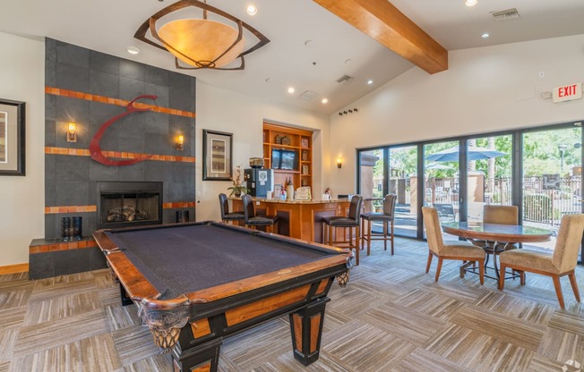 A pool table is in the middle of a room with a fireplace and a bar.