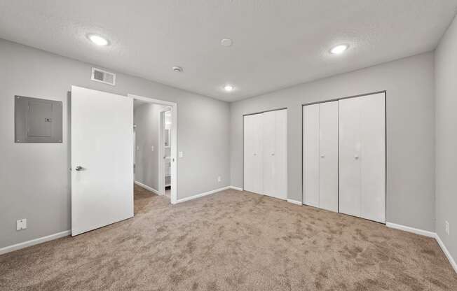 an empty room with mirrored closet doors and carpet