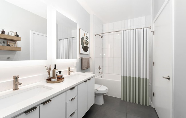 A white bathroom with a toilet, sink, and shower.