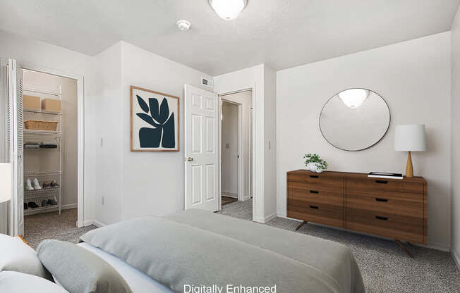 A bedroom with a bed, dresser, mirror and walk in closet at The Highlands Apartments in Elkhart, IN