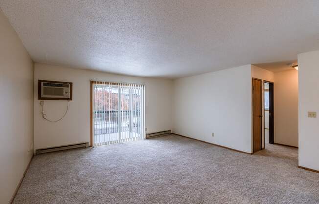 the living room of an apartment with a sliding glass door. Fargo, ND West Oak Apartments.