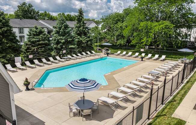 A pool surrounded by chairs and trees