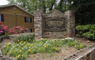 a sign for the cooperstown apartment homes sign in front of a brick building