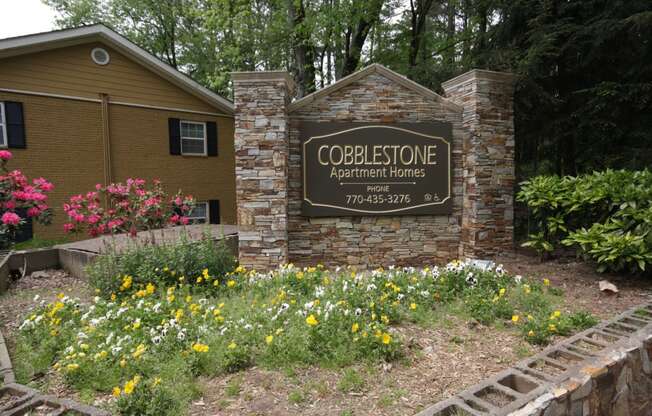 a sign for the cooperstown apartment homes sign in front of a brick building