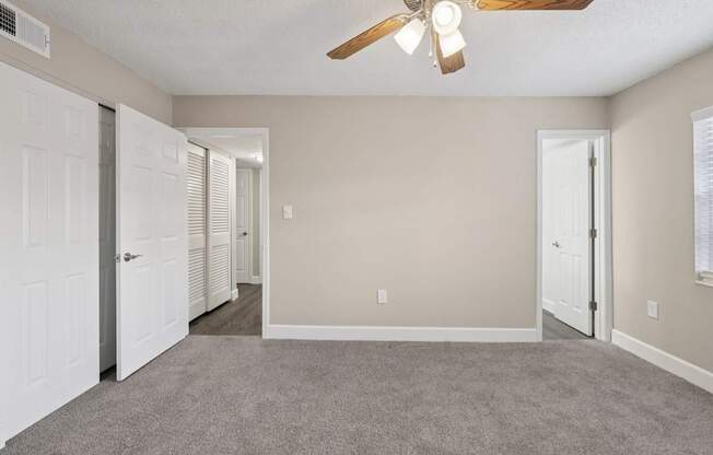 A room with a ceiling fan and carpeted floor.