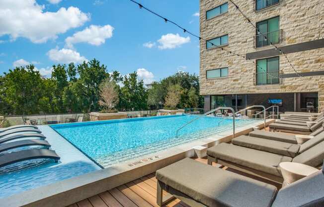 a pool with lounge chairs and a building in the background