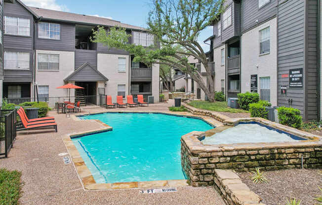 A swimming pool surrounded by a stone wall and chairs.
