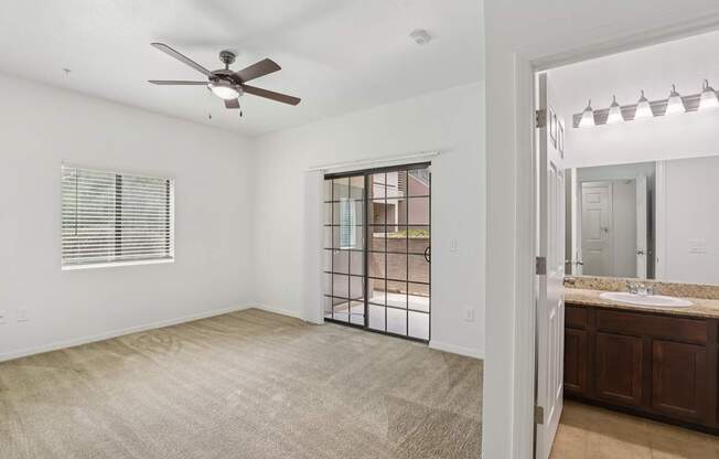A spacious room with a ceiling fan and a sliding glass door leading to a backyard.