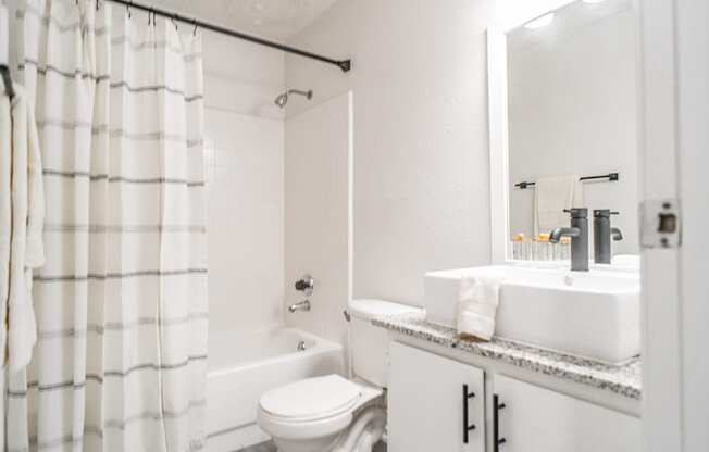 a white bathroom with a shower and a sink and a toilet