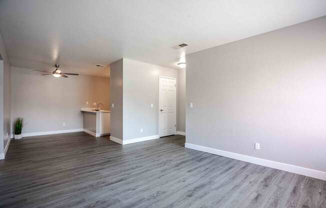 an empty living room with wood floors and a ceiling fan