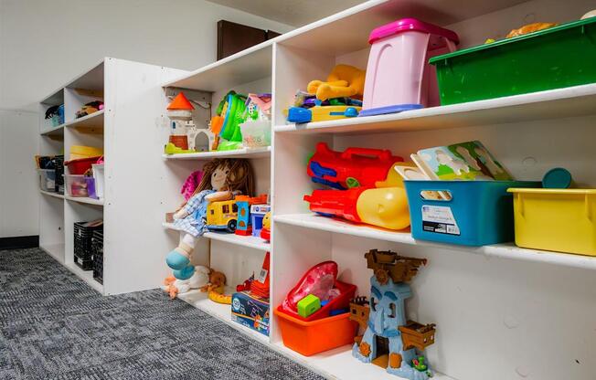 A white shelving unit with toys and containers on it at Sutton Hill Apartments, Des Moines, IOWA