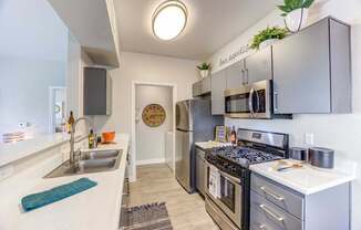 A modern kitchen with stainless steel appliances and a clock on the wall.