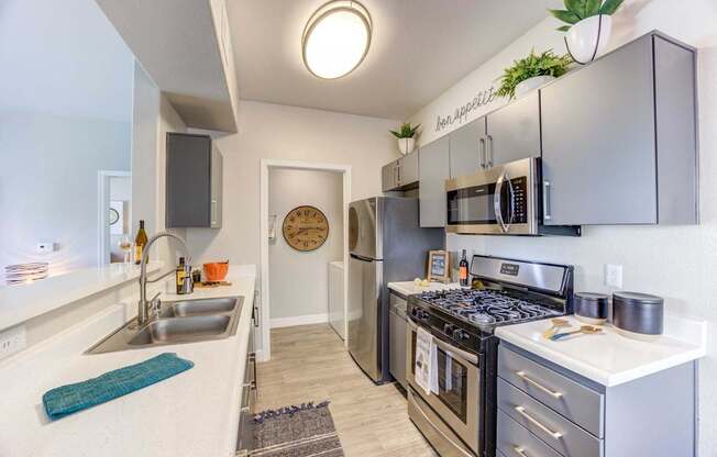 A modern kitchen with stainless steel appliances and a clock on the wall.