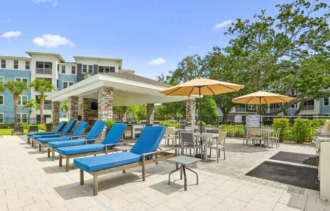 Poolside lounge chairs and umbrellas at Dunedin Commons apartments in Dunedin, FL