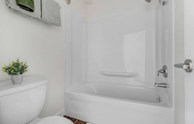 a white bathroom with a white toilet and a bath tub