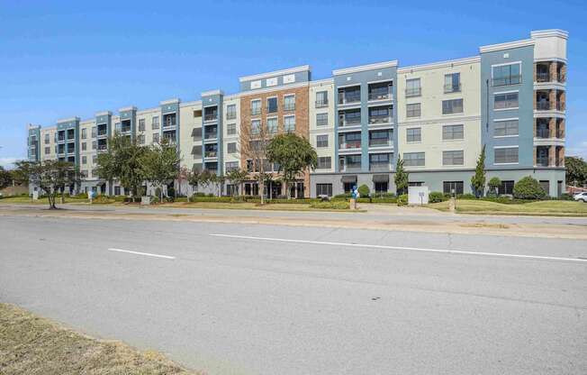 A row of apartment buildings with trees in front.