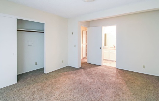 an empty living room with white walls and a door to a bathroom