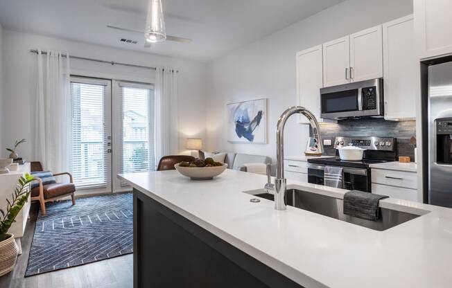 an open kitchen and living room with a sink and a microwave