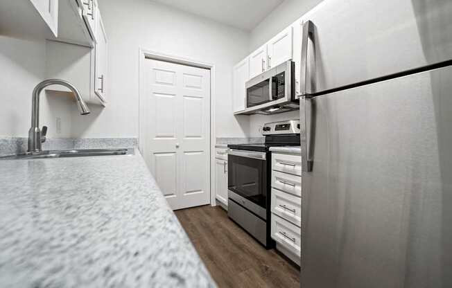 A kitchen with a white counter top and white cabinets.