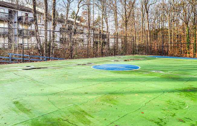 A green tennis court with a blue pool in the middle.
