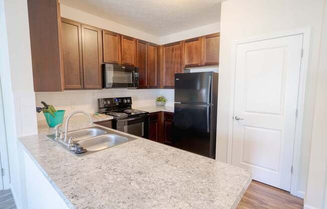A kitchen with a sink, stove, and refrigerator.