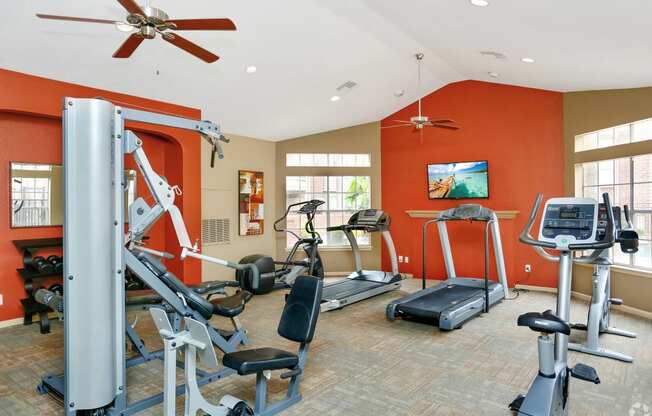 the gym has plenty of exercise equipment and a tv