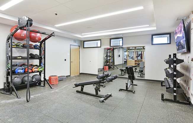 A gym with a variety of equipment including weights and benches.
