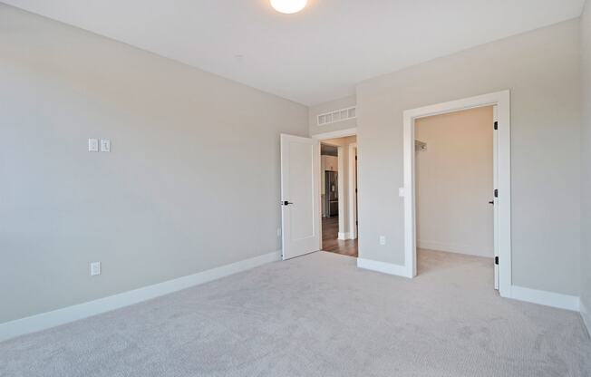 a bedroom with a carpeted floor and a door to a hallway