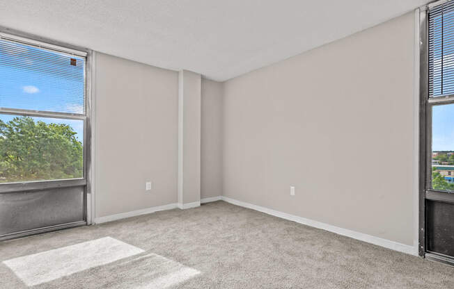 an empty room with large windows and a carpeted floor